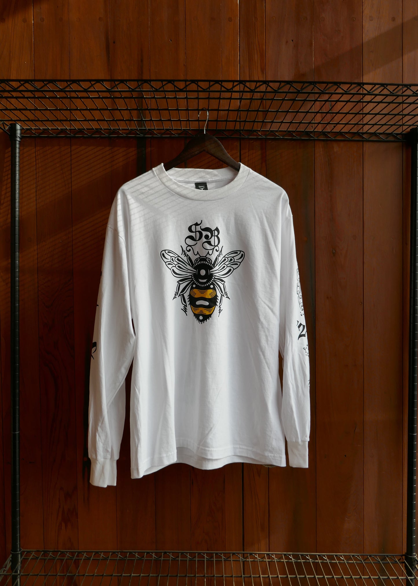 White t-shirt with a bee design on a wooden surface